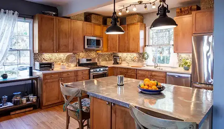 Warm remodeled kitchen with wood cabinetry, pendant lights, and a central island