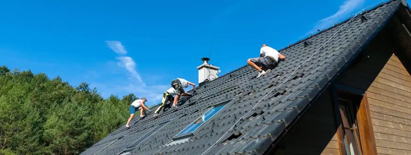 Roofing crew installing shingles on the steep roof of a North Texas home