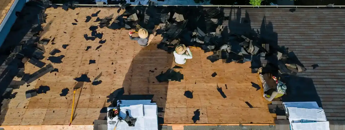 Aerial view of a roofing crew removing worn shingles during an inspection and tear-off